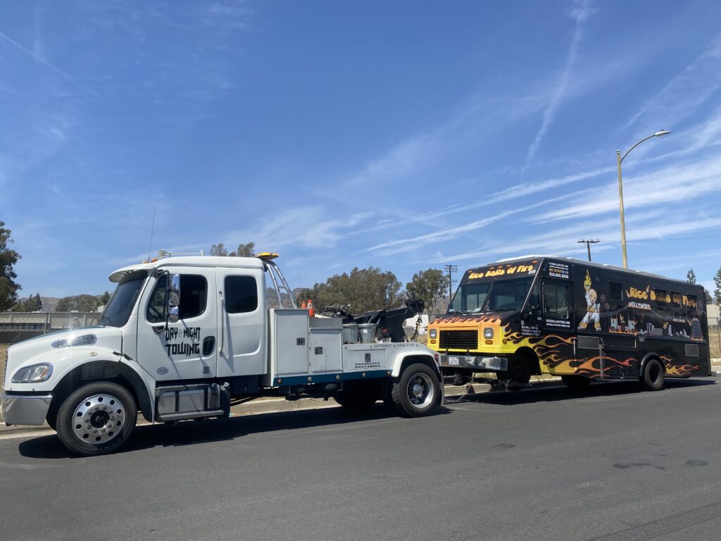 A white truck towing a big truck on the street